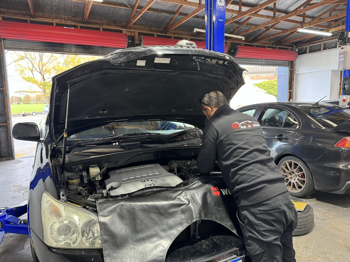 99 Automobiles mechanic in branded workwear servicing a car